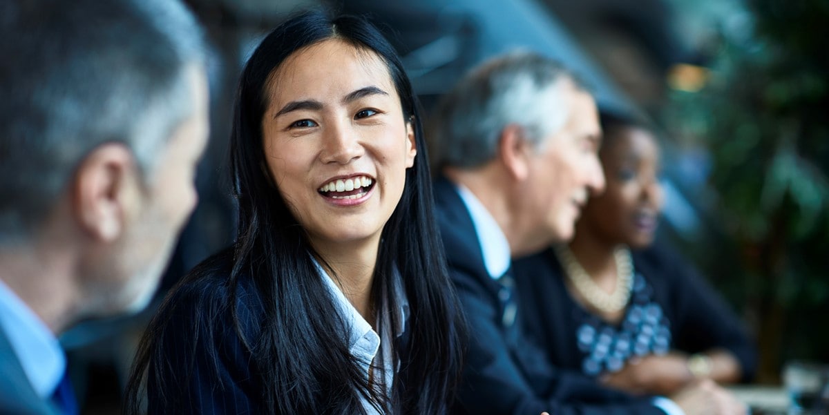 professional woman smiling, sitting next to colleagues