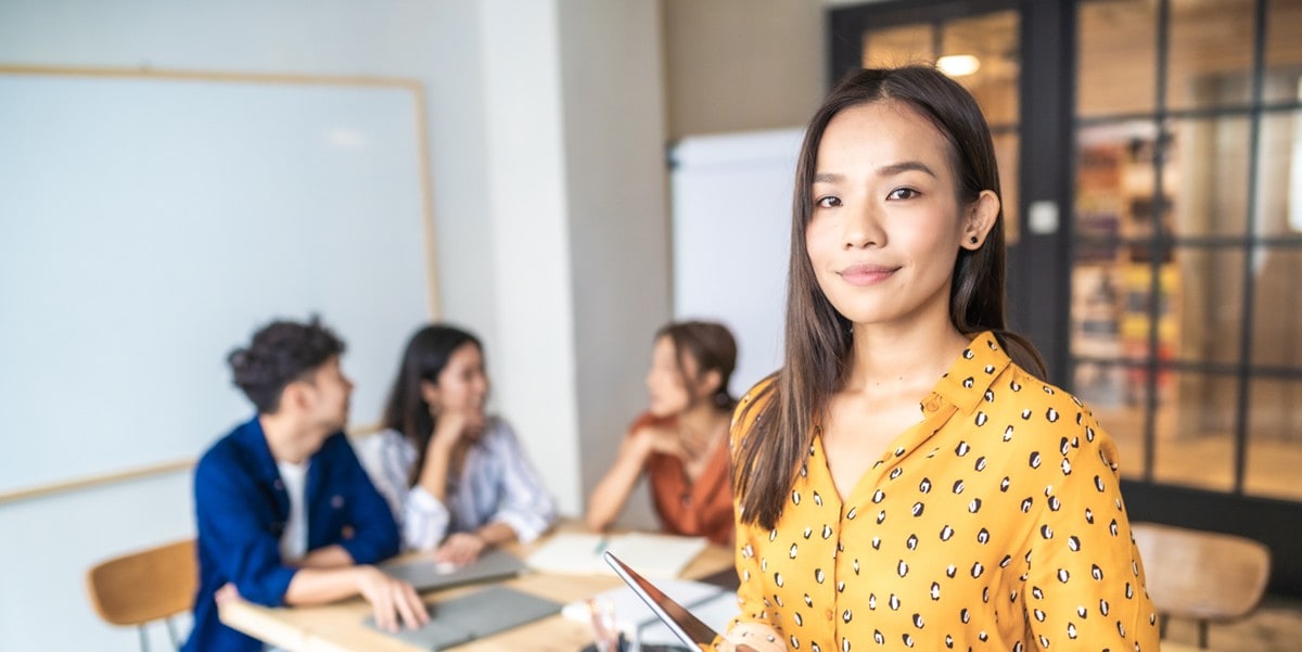 young professional woman in the office, colleagues in the background