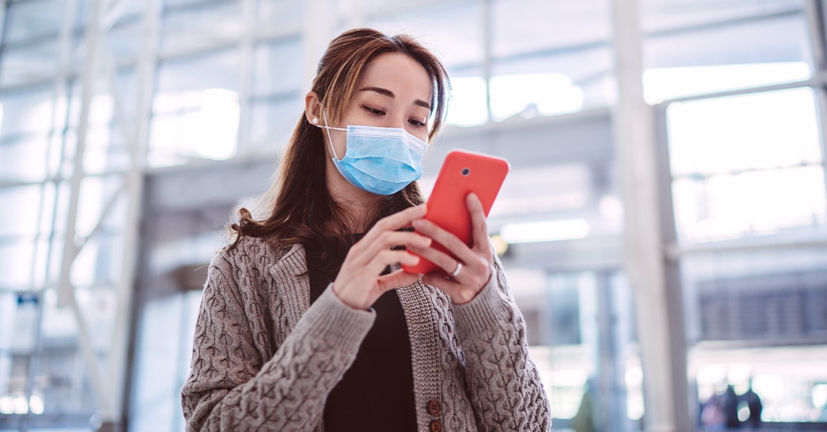 woman with face covering using phone