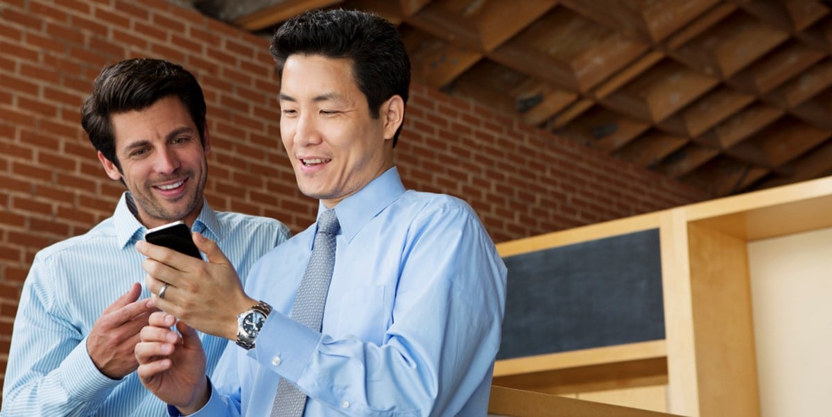 two men in office looking at phone