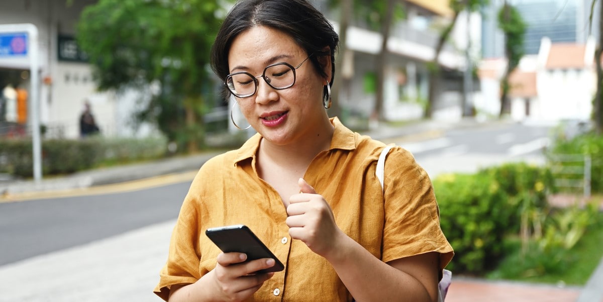 woman using phone walking outside