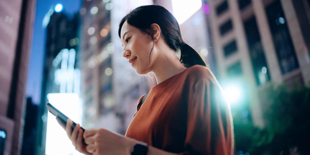 woman outside, city, looking at phone in hand