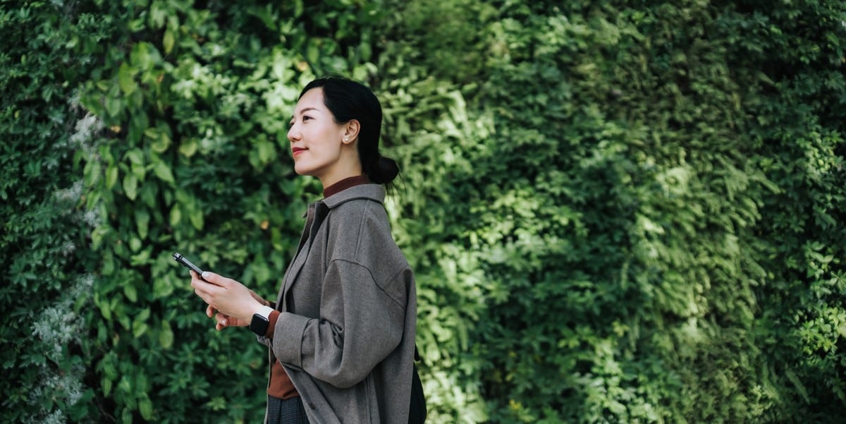 woman standing outside in front of greenery