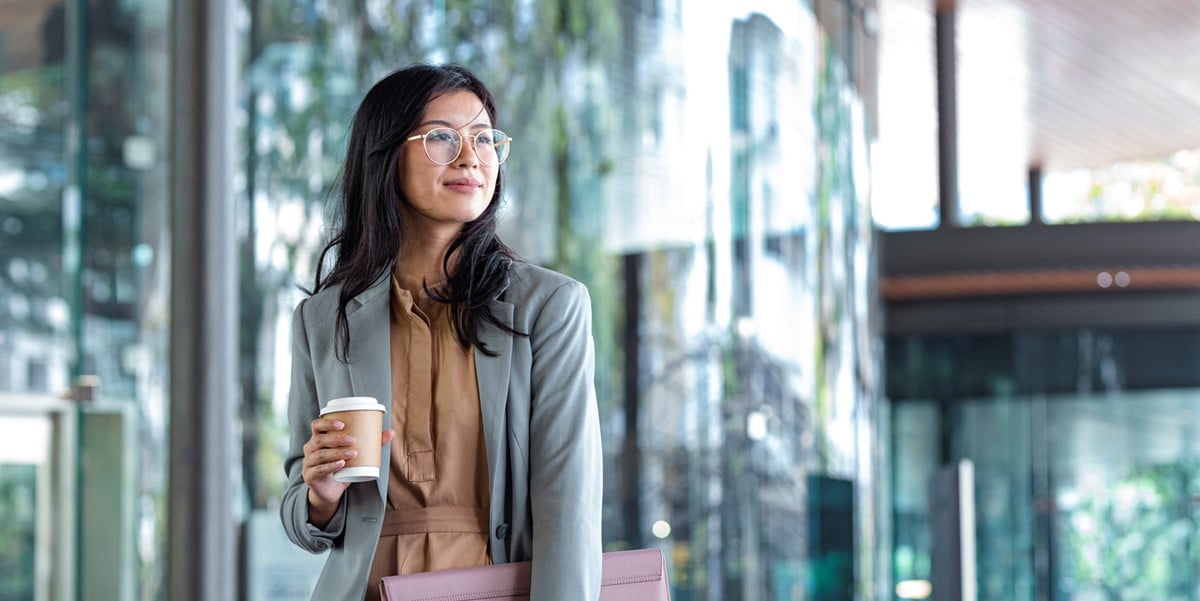 woman walking through office with coffee cup in hand